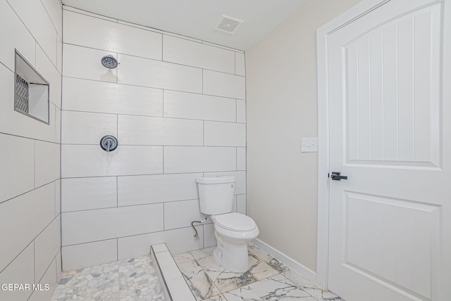 bathroom featuring toilet and a tile shower