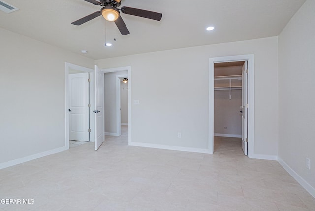 unfurnished bedroom featuring a spacious closet, a closet, and ceiling fan