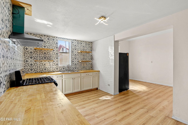 kitchen featuring white cabinetry, sink, wooden counters, stove, and light hardwood / wood-style floors