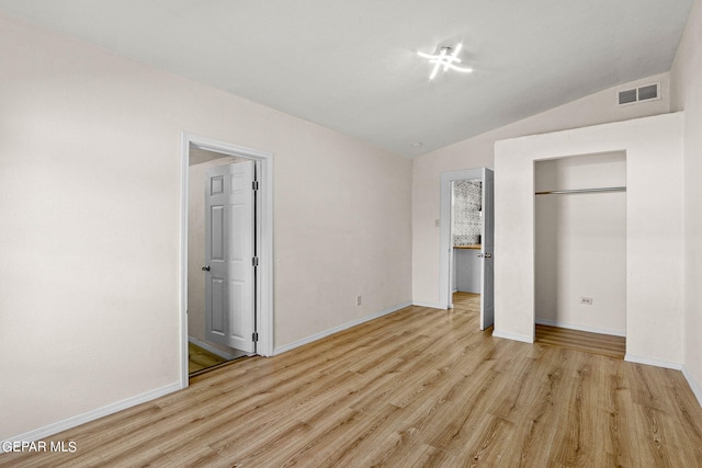 unfurnished bedroom with a closet, lofted ceiling, and light wood-type flooring