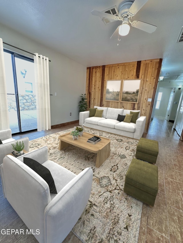 living room featuring dark hardwood / wood-style floors, ceiling fan, and wooden walls