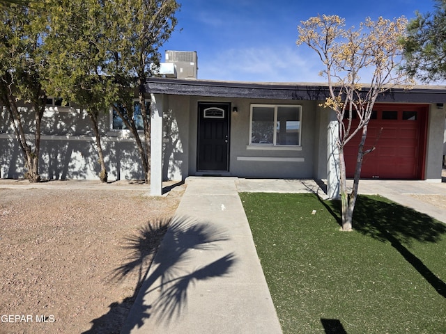 ranch-style home with central AC unit and a garage