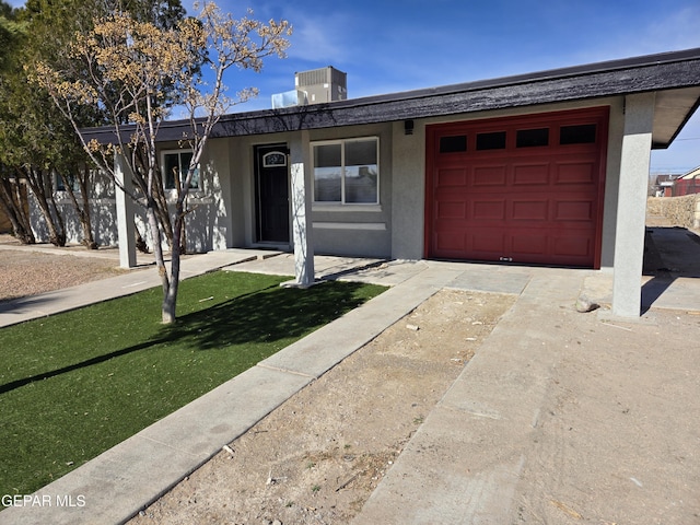 ranch-style home featuring a garage, a front yard, and central AC