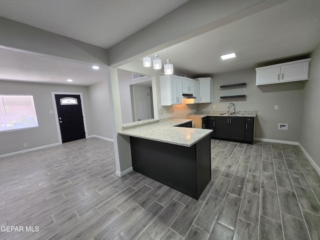 kitchen with pendant lighting, kitchen peninsula, white cabinetry, and sink