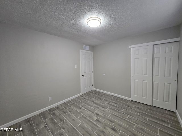 unfurnished bedroom with wood-type flooring, a textured ceiling, and a closet