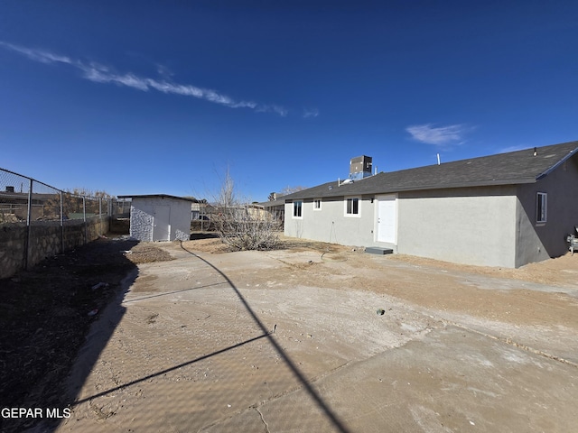 back of house with a storage shed