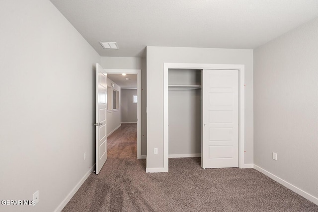 unfurnished bedroom with dark colored carpet and a closet