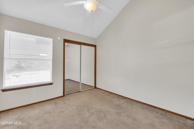 unfurnished bedroom with ceiling fan, vaulted ceiling, light carpet, and a closet