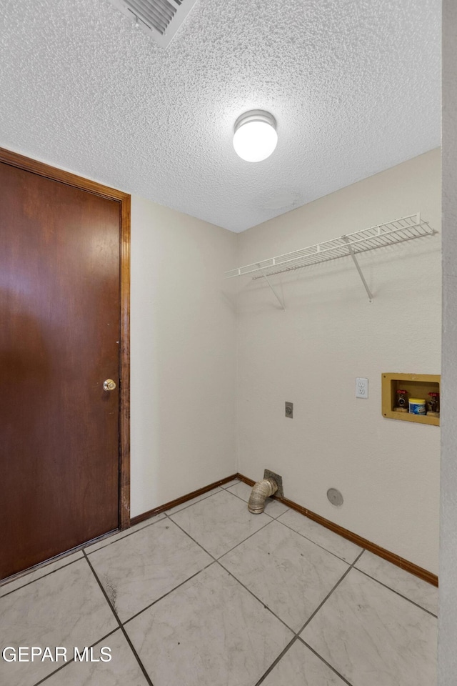 clothes washing area with hookup for an electric dryer, washer hookup, a textured ceiling, and tile patterned flooring