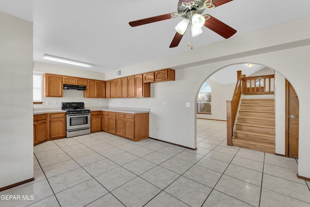 kitchen featuring ceiling fan, light tile patterned floors, a wealth of natural light, and gas range