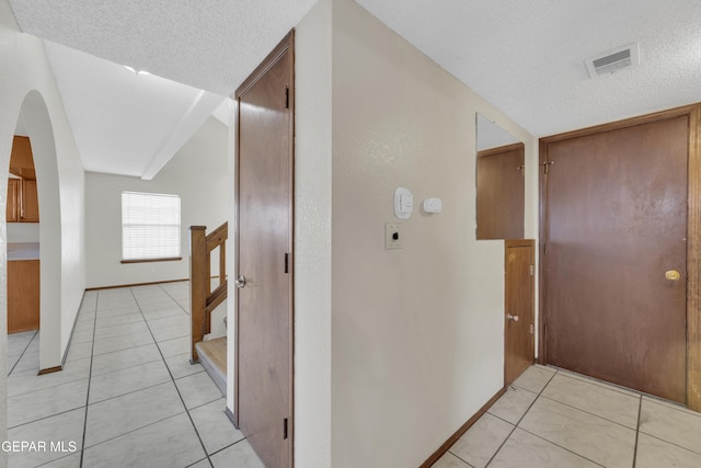 corridor featuring light tile patterned floors and a textured ceiling