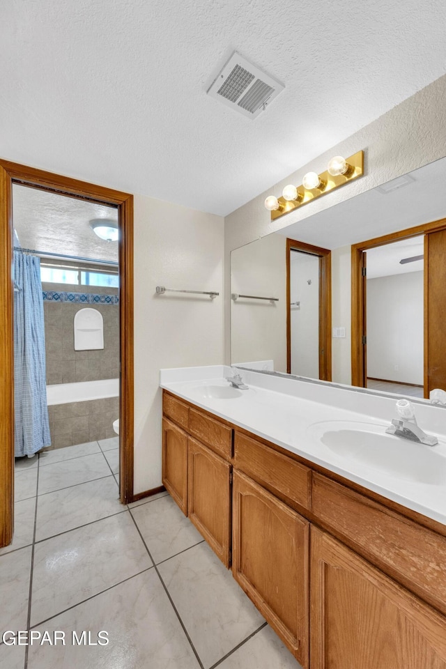 bathroom with tile patterned flooring, vanity, and a textured ceiling