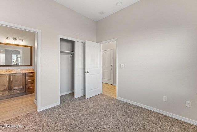 unfurnished bedroom featuring connected bathroom, a closet, light colored carpet, and sink