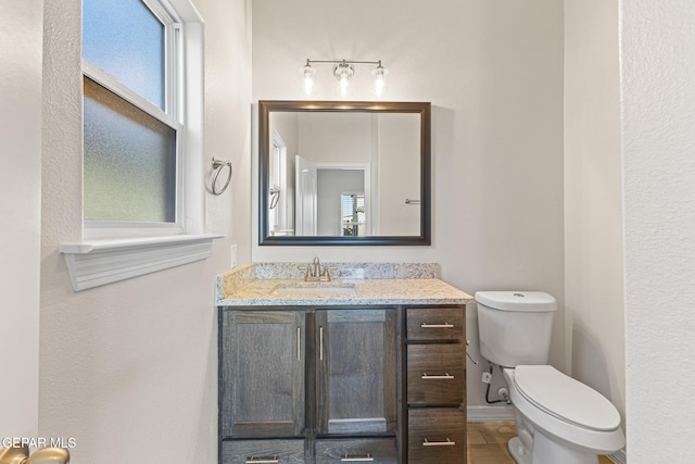 bathroom featuring vanity, toilet, and plenty of natural light