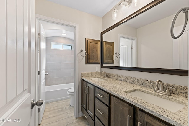 full bathroom with tiled shower / bath, vanity, and toilet