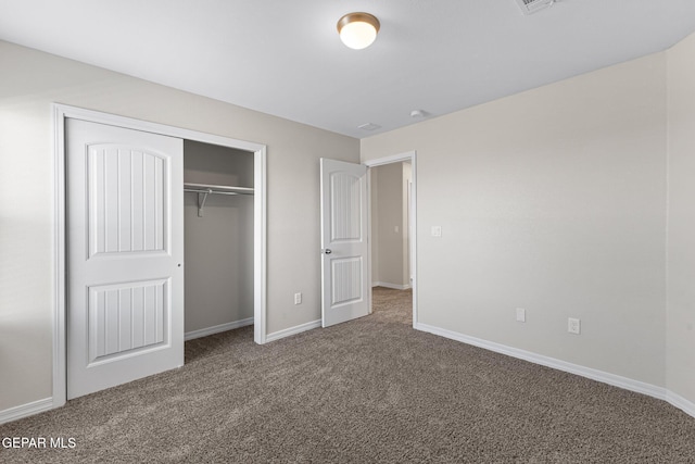 unfurnished bedroom featuring dark colored carpet and a closet