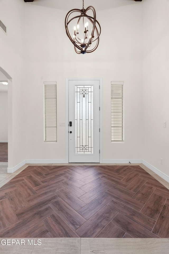 foyer featuring dark parquet floors and a notable chandelier