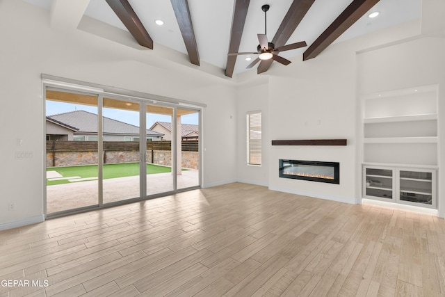 unfurnished living room featuring ceiling fan, built in features, light hardwood / wood-style floors, and plenty of natural light