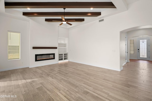 unfurnished living room with beamed ceiling, light hardwood / wood-style floors, built in features, and ceiling fan