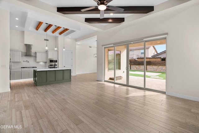 unfurnished living room with ceiling fan, beam ceiling, and light hardwood / wood-style flooring