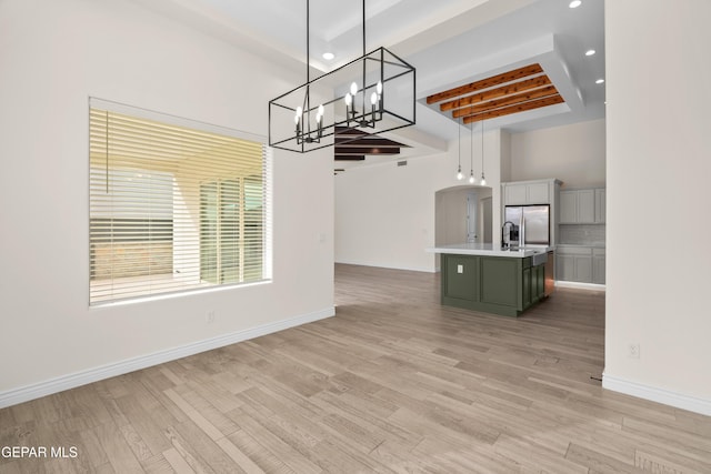 unfurnished dining area featuring beamed ceiling, light wood-type flooring, and sink