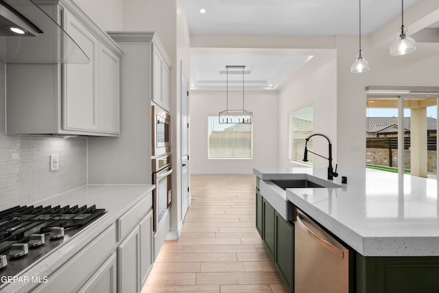 kitchen with sink, decorative backsplash, light stone countertops, an island with sink, and stainless steel appliances