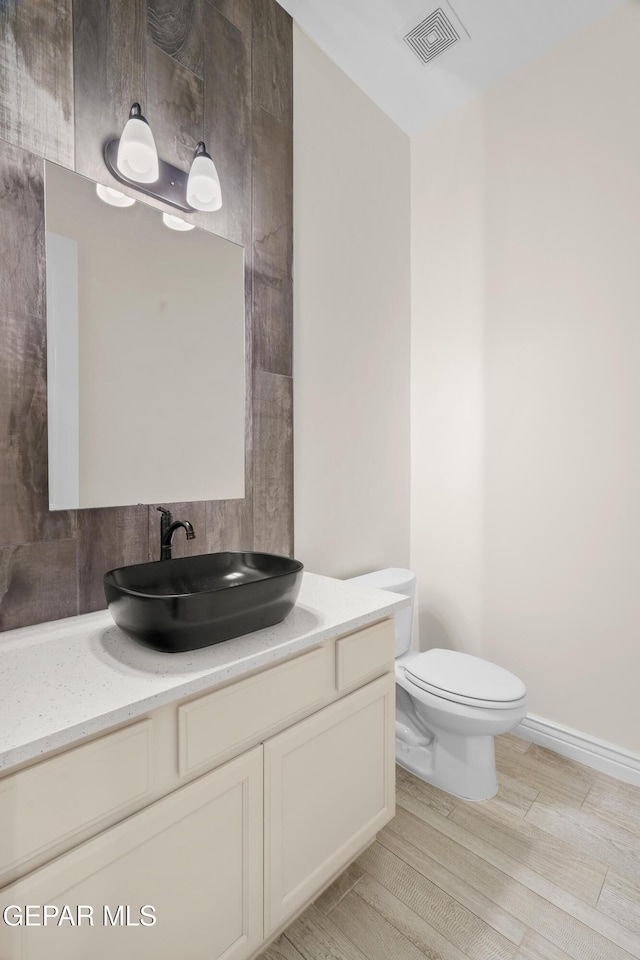 bathroom with wood-type flooring, vanity, and toilet