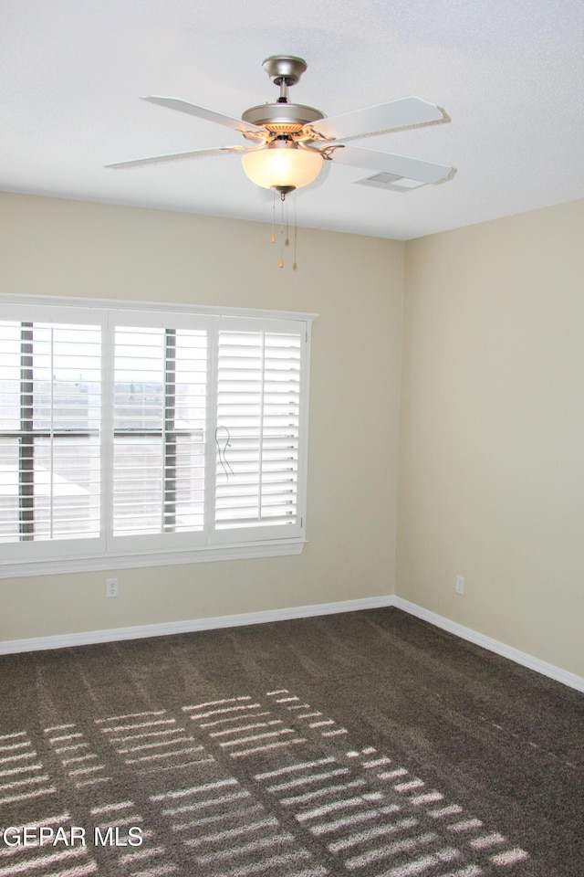 unfurnished room featuring dark colored carpet and ceiling fan