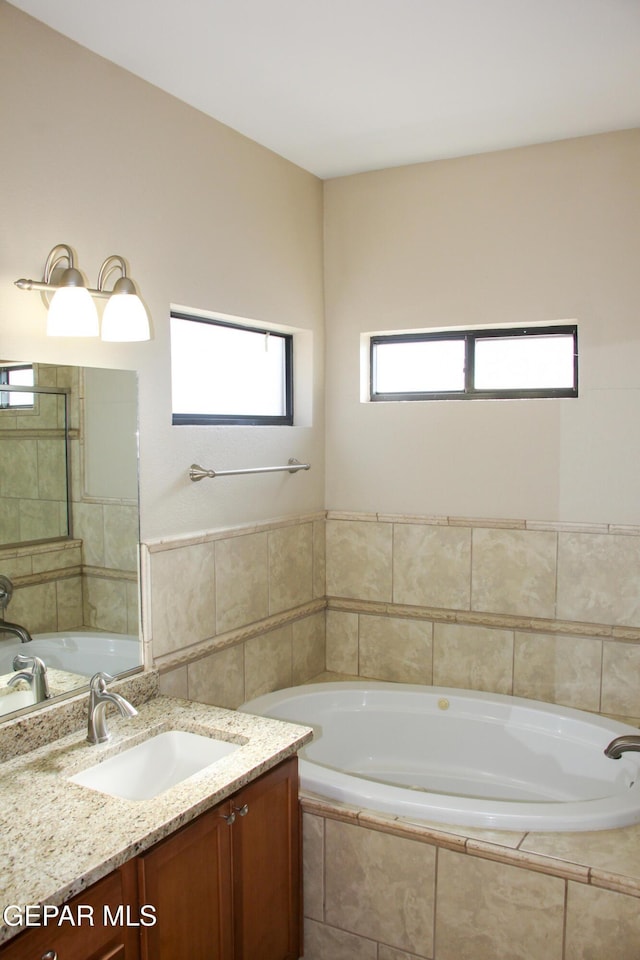 bathroom with vanity and a relaxing tiled tub