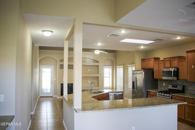 kitchen with sink, decorative backsplash, light tile patterned floors, kitchen peninsula, and stainless steel appliances