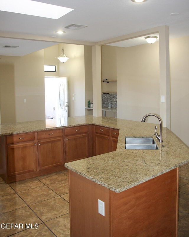 kitchen featuring light stone countertops, pendant lighting, tile patterned floors, and sink