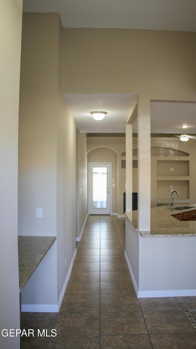 hall featuring dark tile patterned flooring and sink