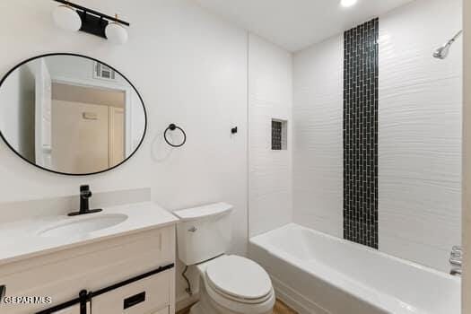 full bathroom featuring vanity, tiled shower / bath combo, and toilet