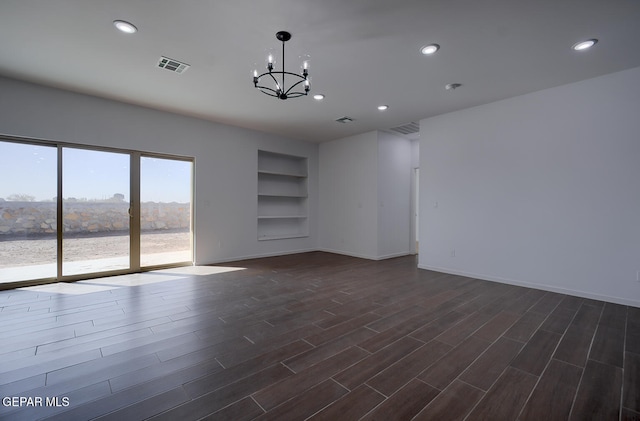 unfurnished room with a chandelier, dark wood-type flooring, visible vents, and built in shelves