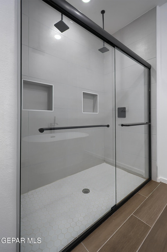bathroom with wood finished floors and a stall shower