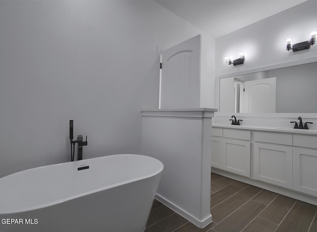 full bath with wood finish floors, a soaking tub, a sink, and double vanity