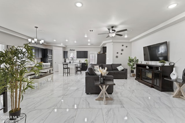 living room featuring ceiling fan with notable chandelier and ornamental molding