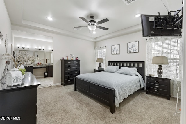 carpeted bedroom featuring a tray ceiling, multiple windows, and ceiling fan