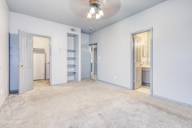 unfurnished bedroom featuring connected bathroom, ceiling fan, light carpet, and a textured ceiling