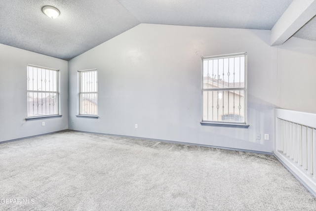 carpeted empty room with a textured ceiling and vaulted ceiling