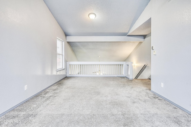 additional living space with a textured ceiling, vaulted ceiling with beams, and carpet floors