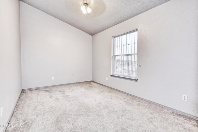 carpeted spare room featuring lofted ceiling and a textured ceiling