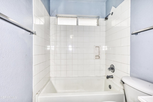 bathroom with toilet and tiled shower / bath