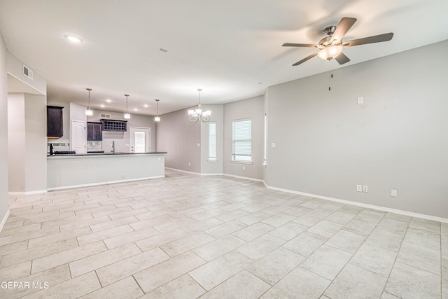 unfurnished living room featuring ceiling fan with notable chandelier and sink