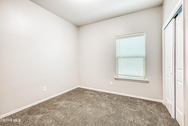 unfurnished bedroom featuring dark carpet and a closet