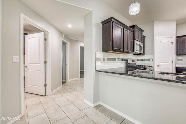 kitchen with dark stone countertops, dark brown cabinetry, and appliances with stainless steel finishes