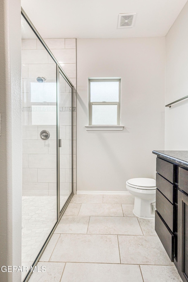 bathroom with tile patterned floors, vanity, an enclosed shower, and toilet