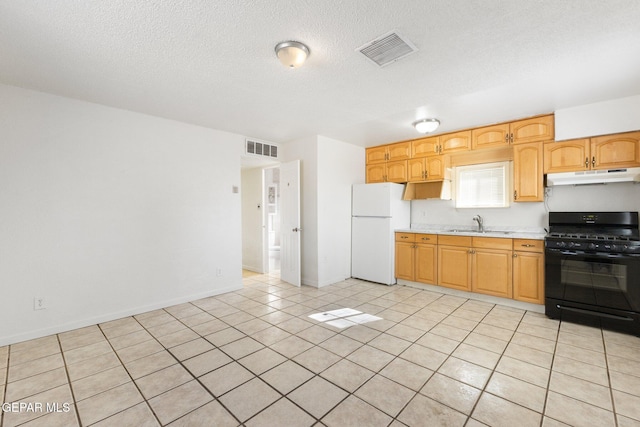 kitchen with a textured ceiling, sink, light tile patterned floors, white refrigerator, and black gas stove