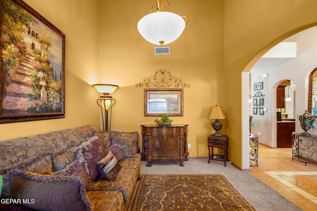 living room with light colored carpet and a towering ceiling