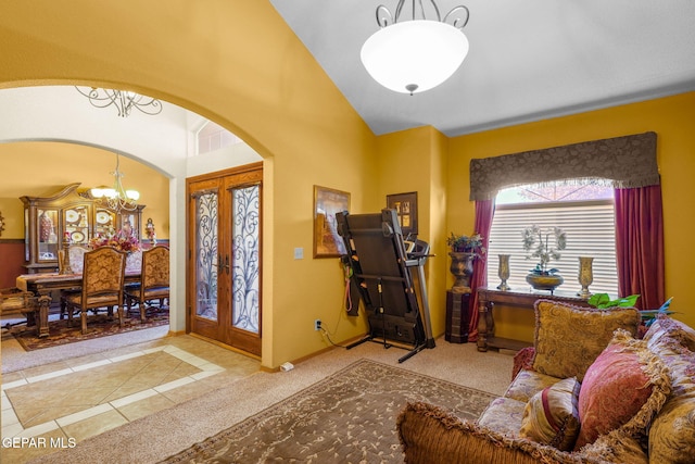 entrance foyer featuring light carpet, lofted ceiling, french doors, and an inviting chandelier